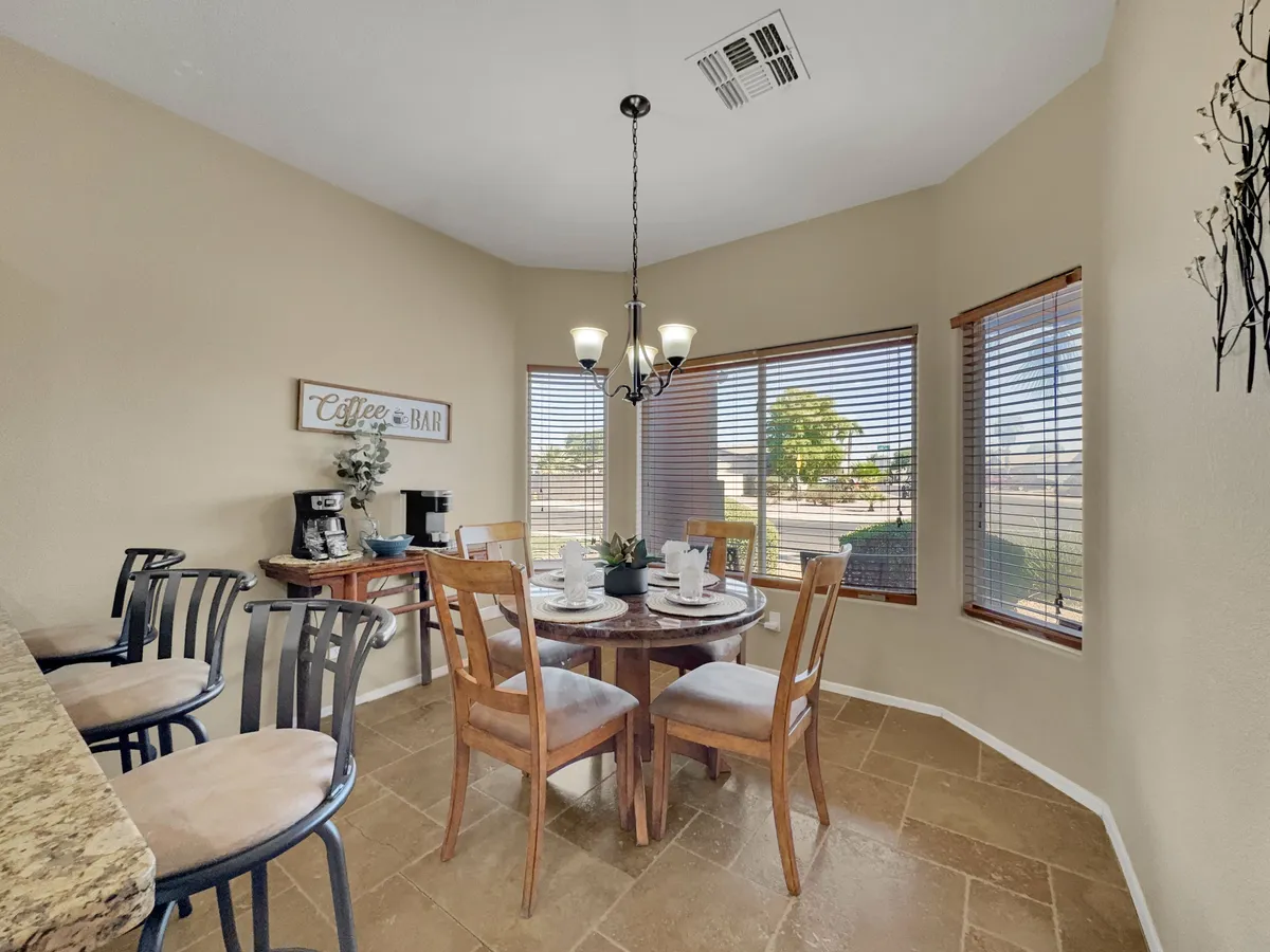 A welcoming dining area with a central dining table, coffee station, and a warm chandelier overhead. The space feels intimate and is perfect for family meals or quiet mornings.