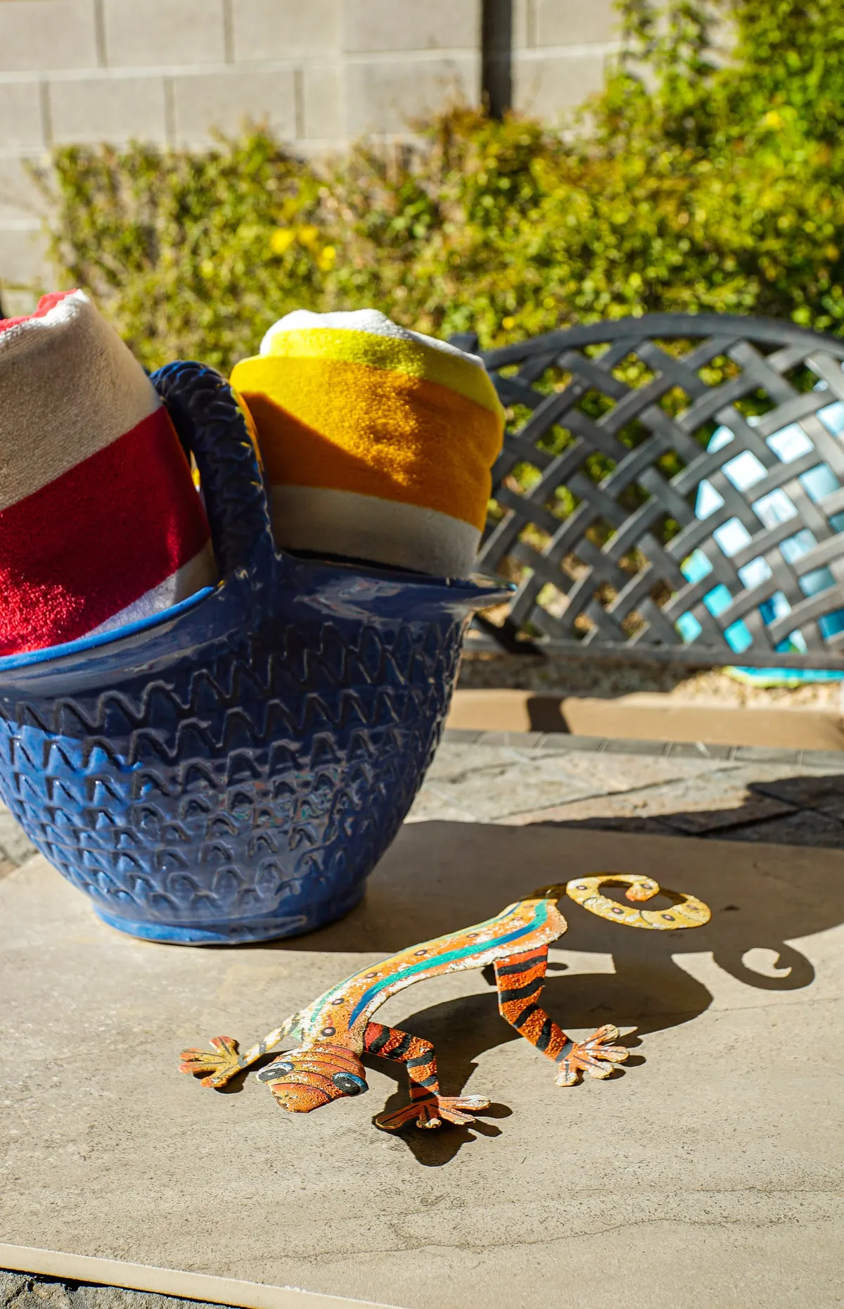 A cheerful, close-up scene beside the pool featuring colorful towels, a decorative lizard, and a blue basket. The playful details evoke vibrant, playful moments—perfect for children and families making the most of sunny days by the water.